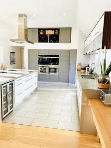 a large kitchen with white cabinets and a white tile floor at The Thorpe Guesthouse in Huntingdon
