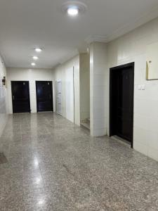 an empty room with white walls and black doors at AlSultan Apartments in Umm Lujj