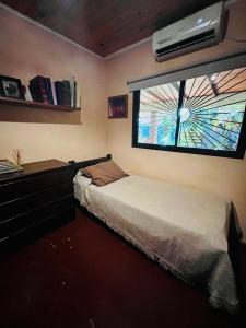 1 dormitorio con 1 cama y ventana con ventilador en Casa Jaguar en Puerto Iguazú