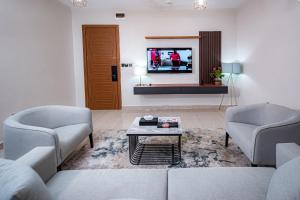 a living room with two chairs and a tv at Wali's Suites in Abuja