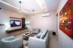 Wali's Suites في أبوجا: غرفة معيشة مع أريكة وتلفزيون