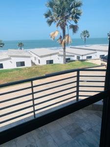 een balkon met uitzicht op de oceaan en een palmboom bij Relax Serviced Ocean 3bedroom Beach Front House in Bijilo