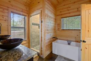 a log cabin bathroom with a tub and a sink at Crystal Moon in Broken Bow