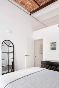 ein weißes Schlafzimmer mit einem Bett und einem Spiegel in der Unterkunft Stylish Apartment with Terrace for Couple or Family in Barcelona