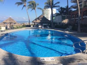 a large blue swimming pool with palm trees and a building at 2 Br Five Star Playa Royale Residences Building in Nuevo Vallarta  +31 photos