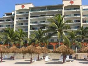 a hotel on the beach with straw umbrellas and palm trees at 2 Br Five Star Playa Royale Residences Building in Nuevo Vallarta 