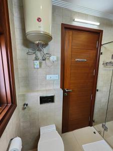 baño con aseo y puerta de madera en Niro GK2, en Nueva Delhi