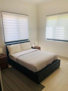 een slaapkamer met een bed en 2 ramen met jaloezieën bij Relax Serviced Ocean 3bedroom Beach Front House in Bijilo