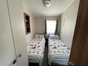 Habitación pequeña con 2 camas y ventana en Ladram Bay Holiday Park D54 en Otterton