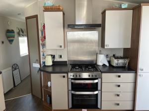 a kitchen with a stove and white cabinets at Ladram Bay Holiday Park D54 in Otterton
