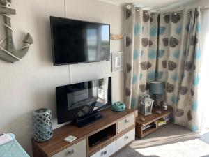 a flat screen tv sitting on a wall with a entertainment center at Ladram Bay Holiday Park D54 in Otterton