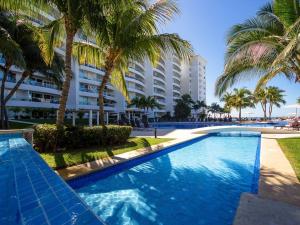 a swimming pool with palm trees and a building at Modern- Renovated- Breathtaking 6th Floor- 3 Bedrooms Villa Magna in Nuevo Vallarta 