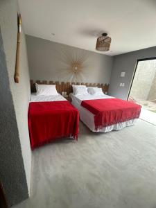 Duas camas num quarto com lençóis vermelhos e brancos em Nauru chalés milagres em São Miguel dos Milagres