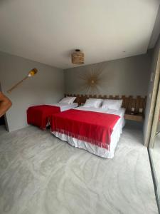 a bedroom with two beds with red and white sheets at Nauru chalés milagres in São Miguel dos Milagres