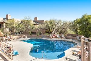 a swimming pool with people sitting on chairs around it at Canyon Crest Condo in Tucson
