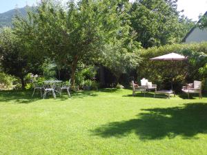 einen Garten mit Tischen und Stühlen im Gras in der Unterkunft Le Gentil Home Chambres d'Hôtes in Arras-en-Lavedan