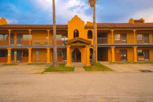 un bâtiment oranger avec des palmiers devant lui dans l'établissement OYO Hotel Kingsville - Hwy 77, à Kingsville