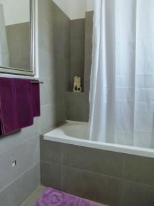 a bathroom with a tub and a shower with purple towels at 'Paradise' by Cnn - Delfini Bay - 3Bed House in Ano Syros