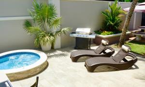 a patio with a hot tub and some chairs and palm trees at Pineridge Hideaway 1 Bedroom Apartment #2 in Arouca