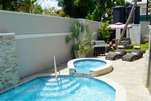 a swimming pool in a backyard with a patio with chairs at Pineridge Hideaway 1 Bedroom Apartment #2 in Arouca