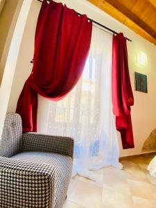 a window with red curtains next to a chair at Casa Calles in Siracusa
