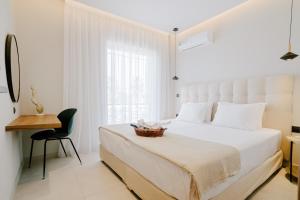 um quarto com uma cama branca com uma cadeira e uma janela em Aelia Prime Experience 1 em Cidade de Kos