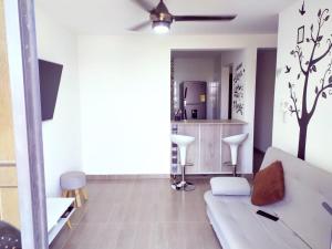 a living room with a white couch and a kitchen at HERMOSO Apartamento con piscina y cerca a PLAYA. in Santa Marta