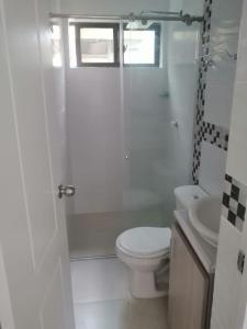 uma casa de banho branca com um WC e um lavatório em HERMOSO Apartamento con piscina y cerca a PLAYA. em Santa Marta