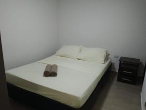 a bed with a pair of shoes sitting on it at HERMOSO Apartamento con piscina y cerca a PLAYA. in Santa Marta