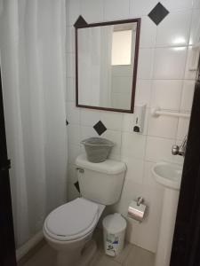 een badkamer met een toilet, een wastafel en een spiegel bij V&B Apartamento in Bogota