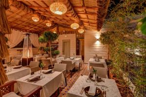 un ristorante con tavoli e sedie bianchi e piante di Riad Diamond Of Marrakech a Marrakech