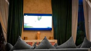 Lodge K في مراكش: غرفة معيشة مع ستائر خضراء وتلفزيون
