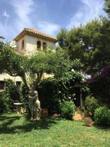 a house with a tree and a statue in the yard at Luz del Mar - vis-à-vis Yachthafen in Denia