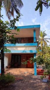 une maison blanche et bleue avec un palmier dans l'établissement Wanderers Stays, à Mangalore