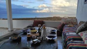 - une table avec de la nourriture et un canapé sur un balcon donnant sur l'océan dans l'établissement EL Faro Surfstay, à Tamri