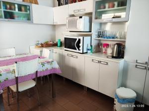 a kitchen with white cabinets and a table and a microwave at Ap central e vista para o Cristo in Encantado