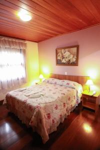 a bedroom with a bed and two lamps and a window at Pousada Recanto Feliz in Campos do Jordão