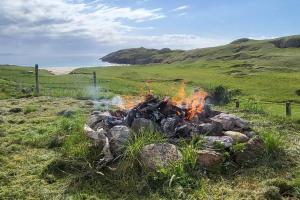 a fire in a pile of rocks in a field at Beachview Villa on Scottish Highland Coast NC500 With Hot Tub in Rhiconich