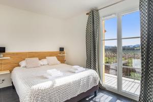 1 dormitorio con cama y ventana grande en Maison Peyrat - Welkeys, en Grimaud