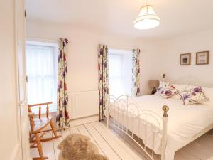 a bedroom with a white bed and two windows at Trigfa in Blaenau-Ffestiniog