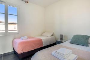 two beds in a room with a window at Maison Peyrat - Welkeys in Grimaud