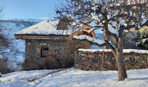 ein Steingebäude im Schnee mit einem Baum in der Unterkunft Bourg Saint Maurice Les Arcs - maisonnette grand confort dans charmant village de montagne ! in Bourg-Saint-Maurice
