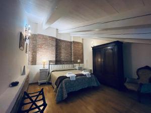 een slaapkamer met een bed en een stoel in een kamer bij Relais Palazzo Paleologi Sec.XIV in Lu