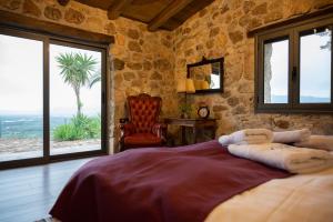 a bedroom with a bed and a chair and windows at Silo Stone House 