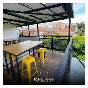 una terraza con una mesa y dos taburetes amarillos en Casa hotel Los Laureles, en Medellín