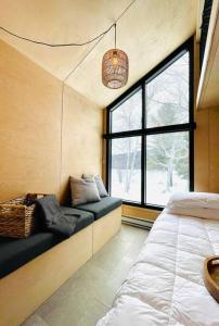 1 dormitorio con cama y ventana grande en Micro maison le Nordik en Saint Zenon