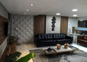 ein Wohnzimmer mit einer schwarzen Couch und einem Tisch in der Unterkunft Israel Flat Apt 122 in João Pessoa