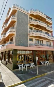 a building with tables and chairs in front of it at Apto com Varandas 103 - Balneário Arroio do Silva - 3 minutos do Mar in Arroio do Silva