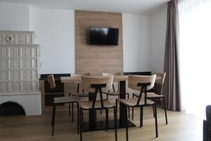 une salle à manger avec une table et des chaises ainsi qu'une télévision murale. dans l'établissement DolceAmbiez Apartments, à Dorsino