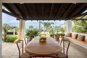 un tavolo e sedie in legno su un patio di Villa a 300 Mt. dal Mare (Magaggiari) con campo da tennis a Cinisi